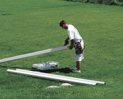 RainMaster-seamless-gutters man laying out white gutters on grass prior to installation - Rain Master Seamless Gutters