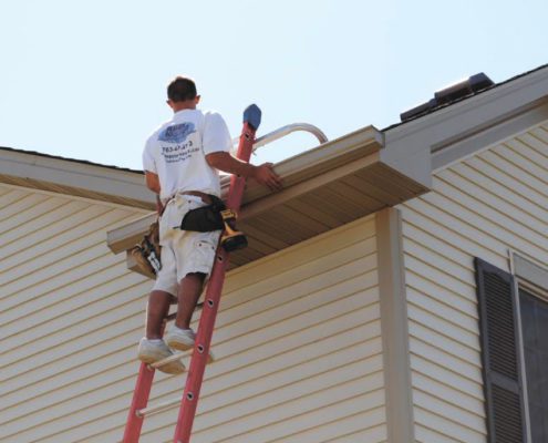 RainMaster-seamless-gutters man adjusting gutter system on the side of a house - Rain Master Seamless Gutters