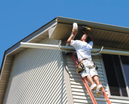 RainMaster-seamless-gutters man on ladder drilling a newly installed gutter - Rain Master Seamless Gutters