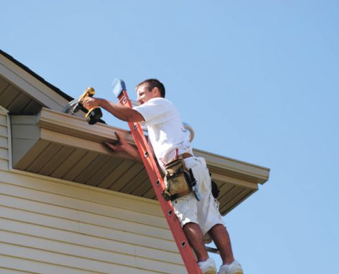 RainMaster-seamless-gutters man on ladder drilling a newly installed gutter - Rain Master Seamless Gutters