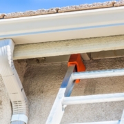 white seamless gutters with a metal ladder - Rain Master Seamless Gutters