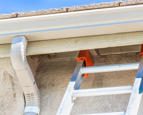 white seamless gutters with a metal ladder - Rain Master Seamless Gutters