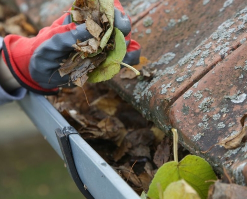 person wearing gloves cleaning gutters - Rain Master gutter cleaning