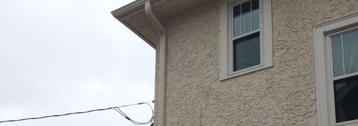 house with stucco siding - Rain Master seamless gutter installation near Anoka