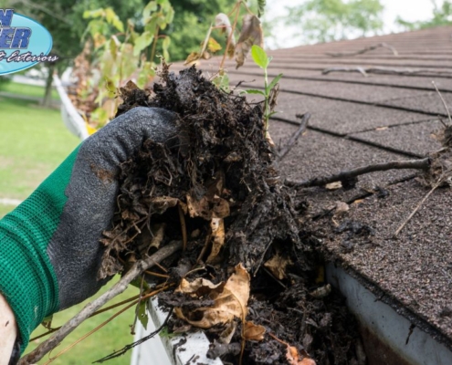 person wearing green glove cleaning gutters - Rain Master gutter cleaning