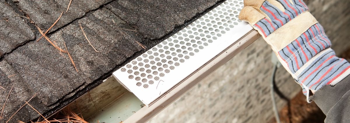 person installing a white leaf guard on to their gutter - Rain Master gutter guards