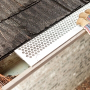 person installing a white leaf guard on to their gutter - Rain Master gutter guards