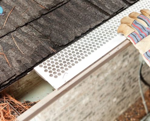person installing a white leaf guard on to their gutter - Rain Master gutter guards