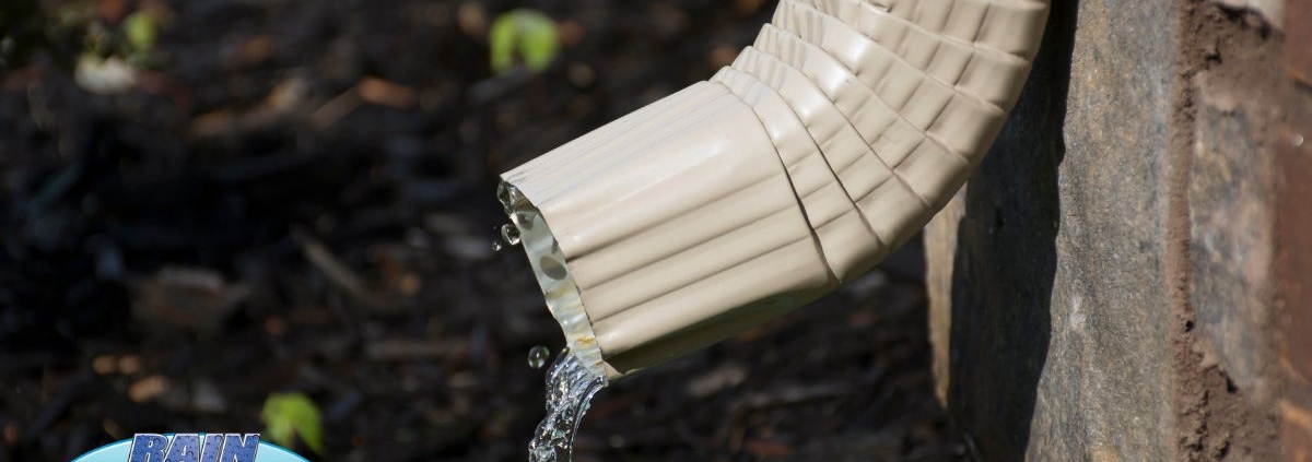 tan colored downspout with water coming out - Rain Master Gutters for Drainage