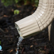 tan colored downspout with water coming out - Rain Master Gutters for Drainage