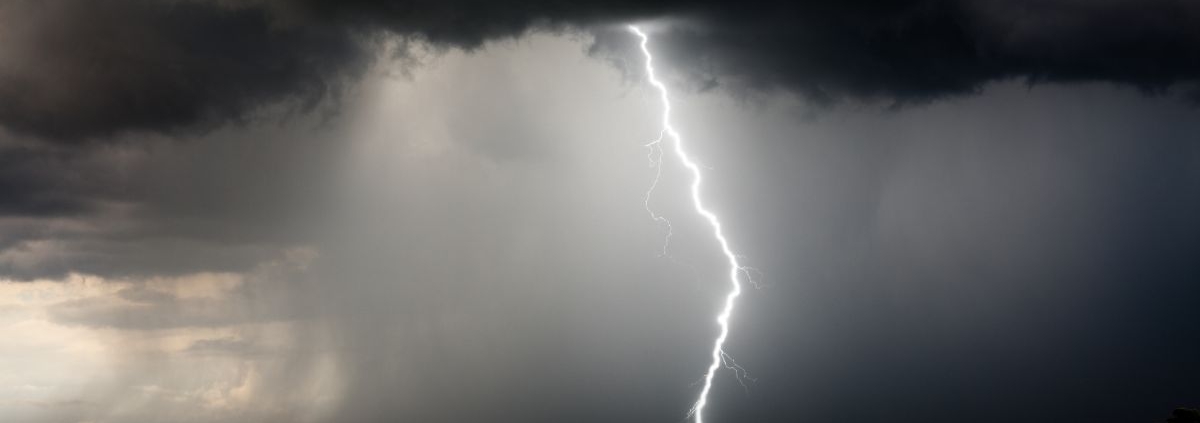 empty grass field with a thunderstorm coming through - Rain Master Seamless Gutters