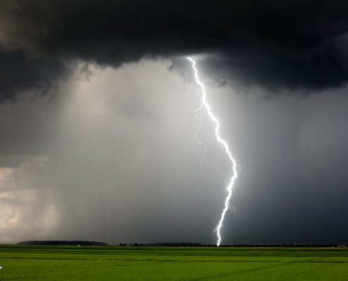 empty grass field with a thunderstorm coming through - Rain Master Seamless Gutters